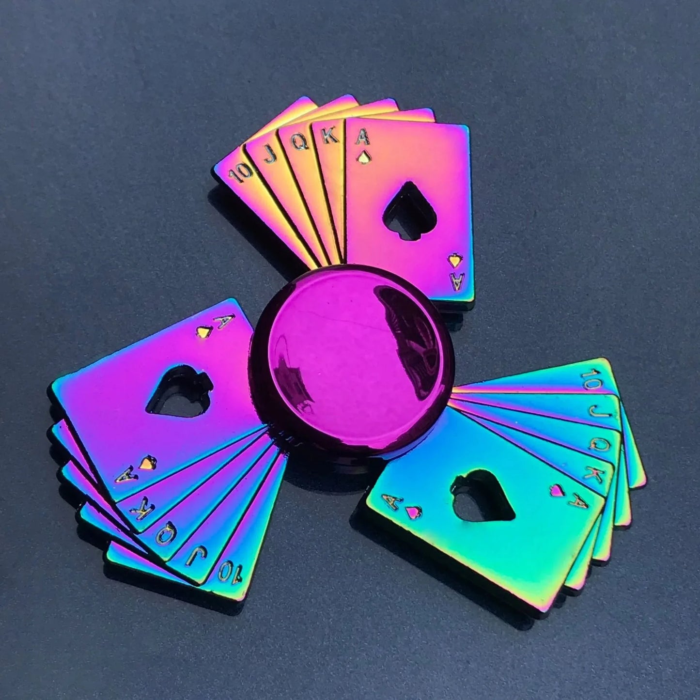 Holographic playing cards fanned out on a dark surface with a magnifying glass.