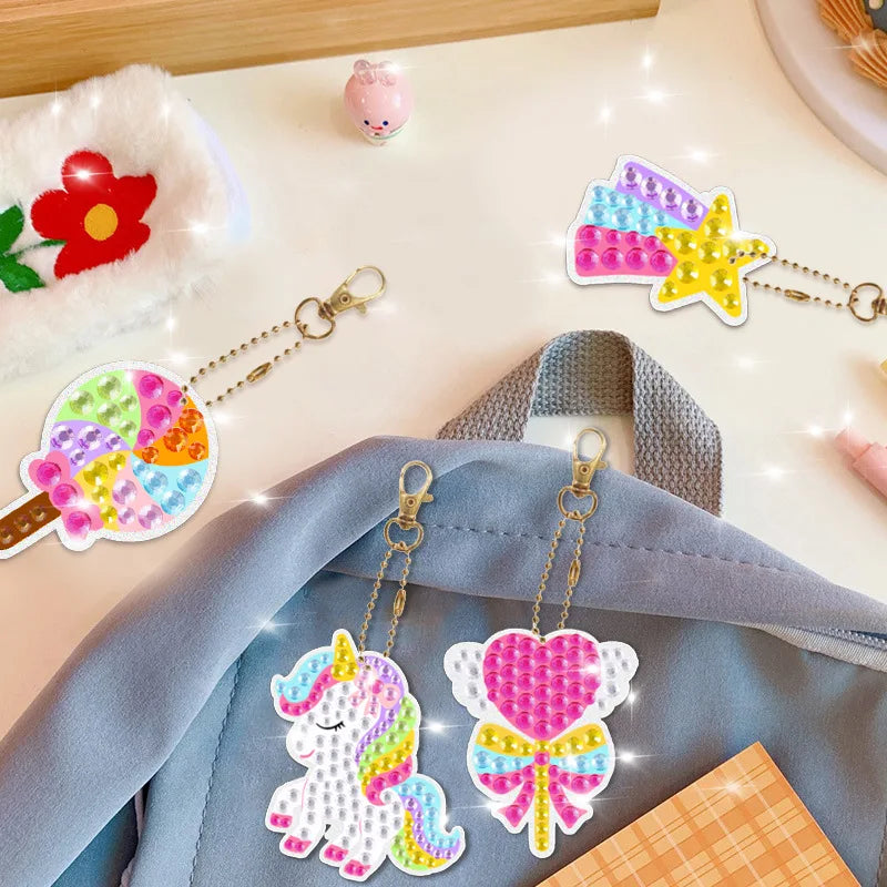 Colorful keychains with a unicorn and heart design on a backpack, with a pink flower and other items in the background.