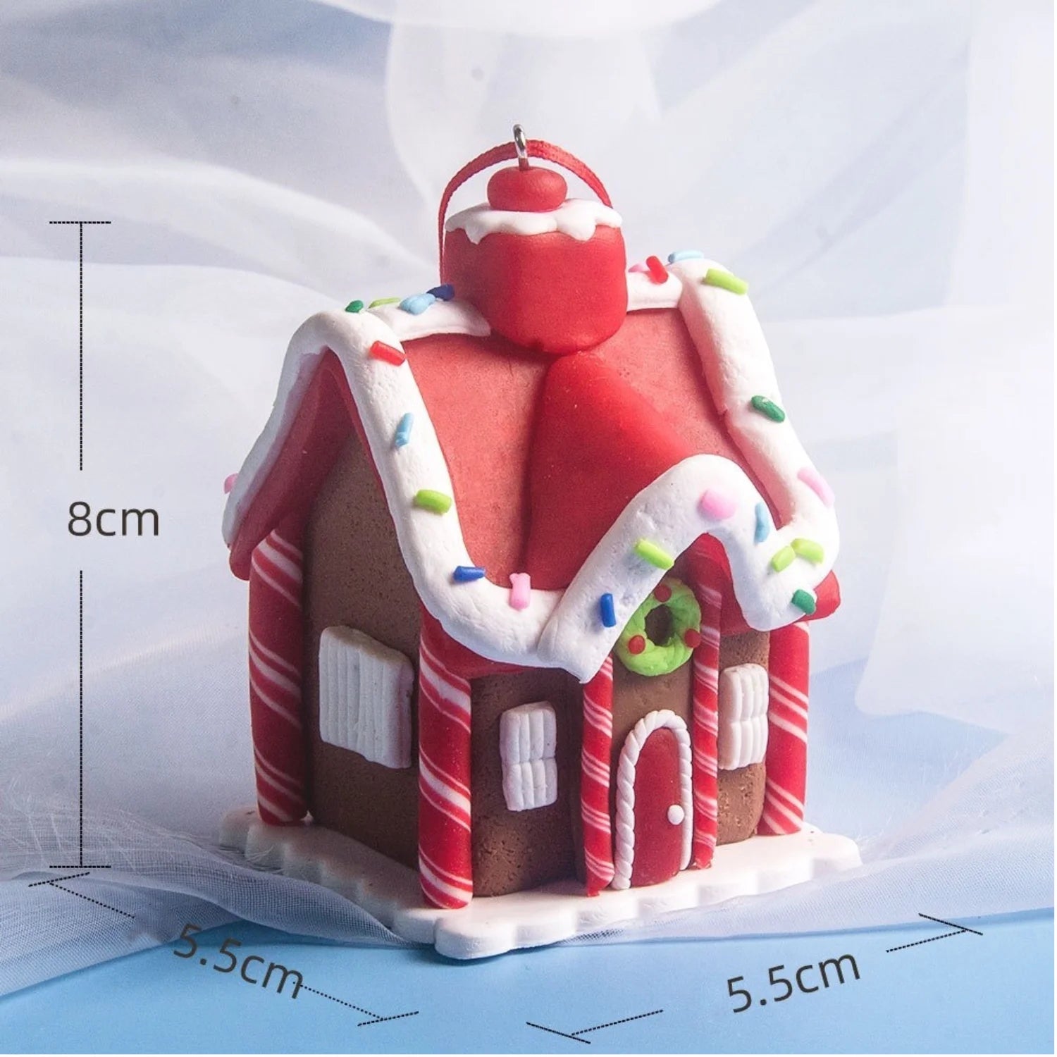 Gingerbread house-shaped candle with measurements on a light blue background