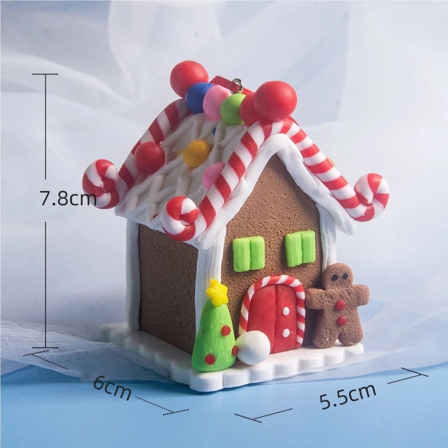 Gingerbread house ornament with candy cane roof and measurements on a light blue background