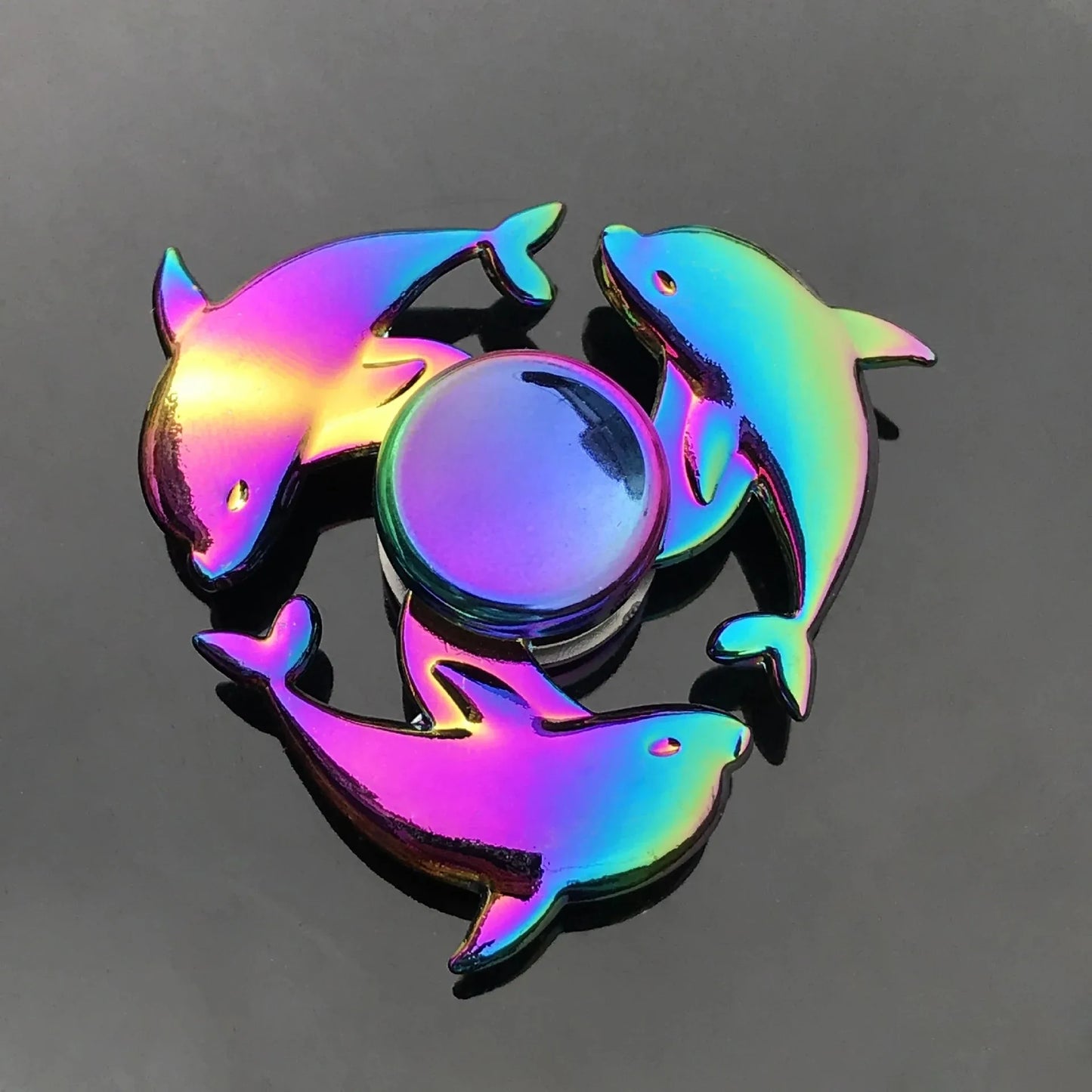 Colorful fidget spinner with four dolphin-shaped handles on a dark background
