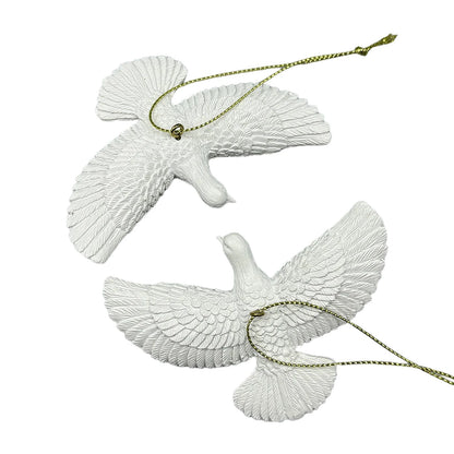 Two white dove ornaments with gold chains on a white background