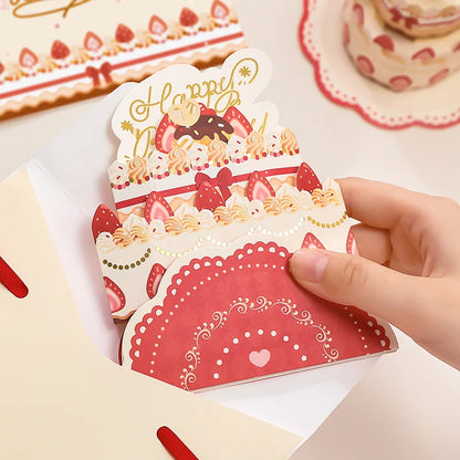 Hand holding a decorative card with cake design and 'Happy Birthday' text.