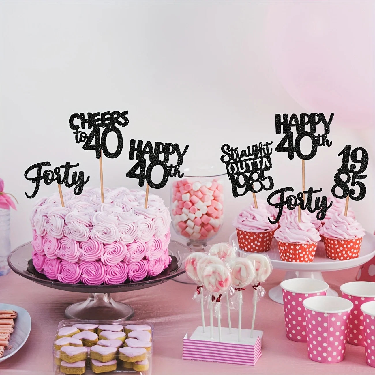 40th birthday celebration setup with pink cake, cupcakes, and decorative toppers.