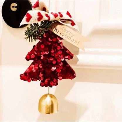 A red sequined Christmas tree ornament with a gold bell hanging below, decorated with a red and white patterned ribbon, green pine branches, and a beige ribbon that says 'Merry Christmas!'.