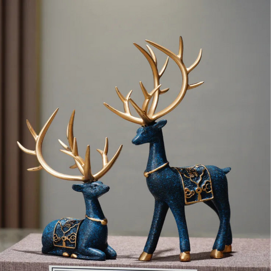 Two decorative blue deer figurines with gold antlers on a neutral background