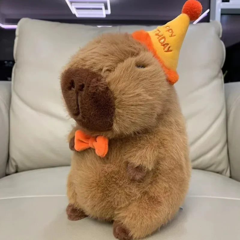 Plush toy capybara wearing a party hat and bow tie on a car seat.
