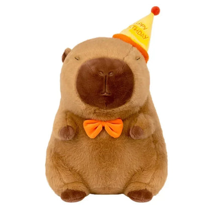 Plush toy capybara wearing a party hat and bow tie on a white background