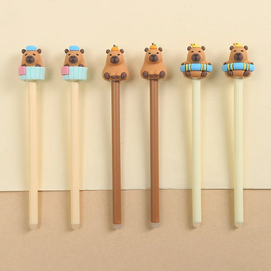 Set of six capybara-shaped pens with colorful hats on a beige background