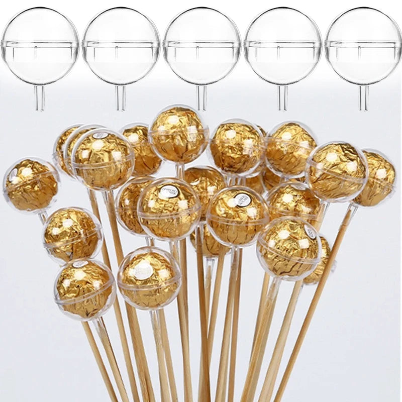 Gold wrapped candies on sticks with clear spherical holders against a white background