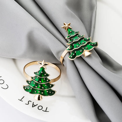 Two green Christmas tree-shaped rings with gold accents on a gray fabric background.