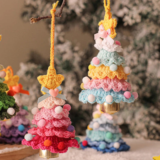 Colorful crocheted Christmas trees with pom-pom details on a blurred Christmas tree background.