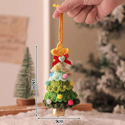 Handmade crocheted Christmas tree ornament with colorful decorations, held by a hand against a blurred indoor background.