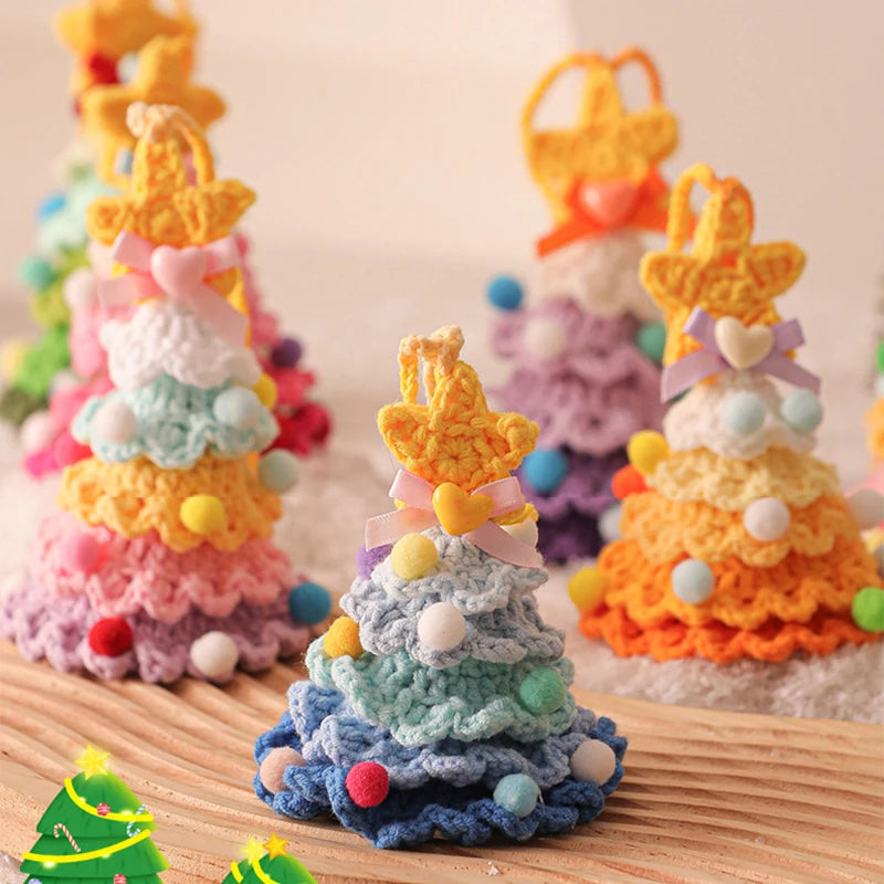 Colorful crocheted Christmas trees with pom-pom decorations on a wooden surface.