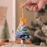 Hand holding a crocheted Christmas tree ornament with measurements indicated.