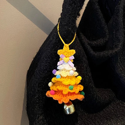 Colorful crocheted orange Christmas tree ornament with a bell on a black surface.