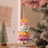 Colorful crocheted Christmas tree ornament held by a hand with measurements indicated.