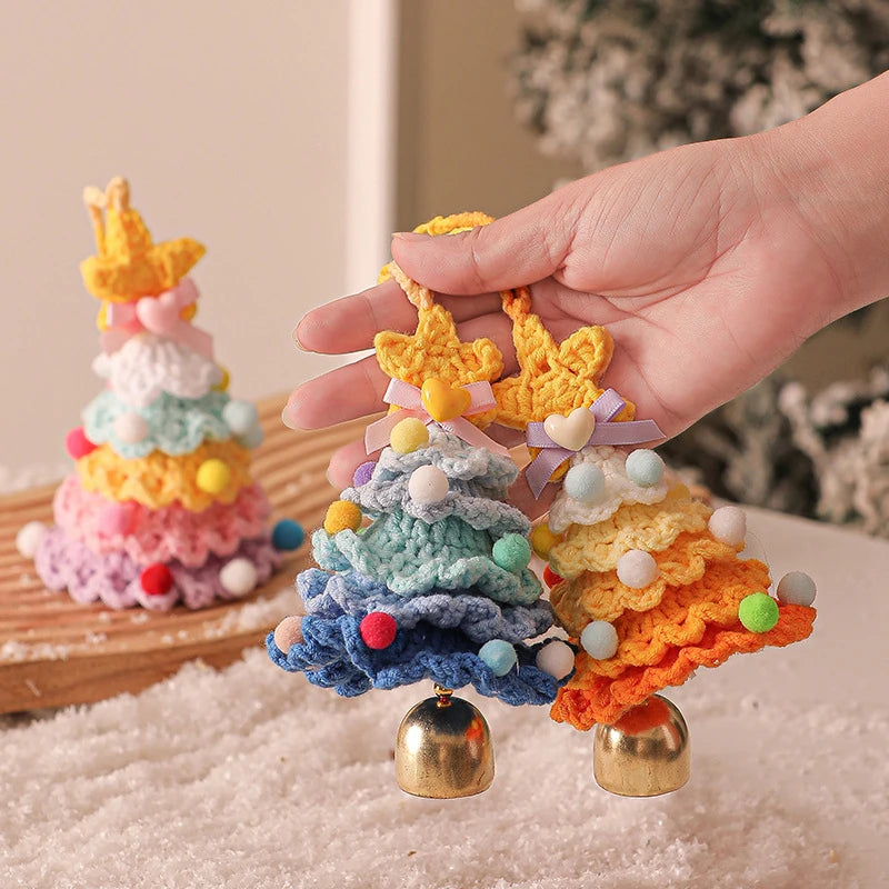 Colorful crocheted Christmas trees with bells on a textured surface.