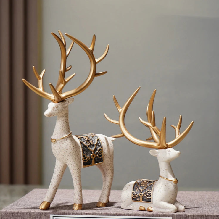 Decorative deer figurines with gold antlers on a gray surface.