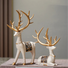 Decorative deer figurines with gold antlers on a gray surface.