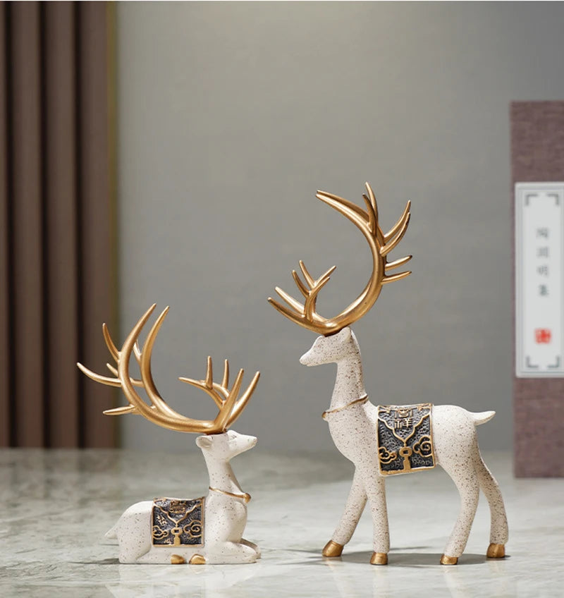 Decorative deer figurines with gold antlers on a neutral background
