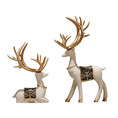 Two decorative deer figurines with gold antlers on a white background