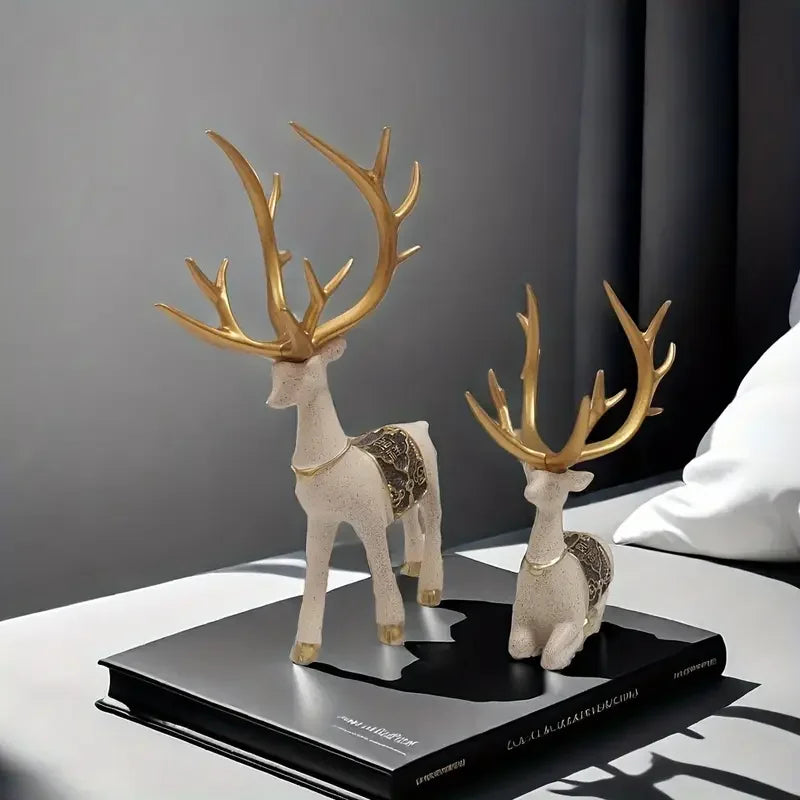 Decorative deer figurines with gold antlers on a book against a gray background