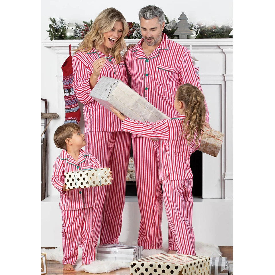 Family in matching red and white striped pajamas opening presents in a festive setting.