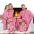 Family of five wearing matching red and white striped pajamas sitting in front of a fireplace.