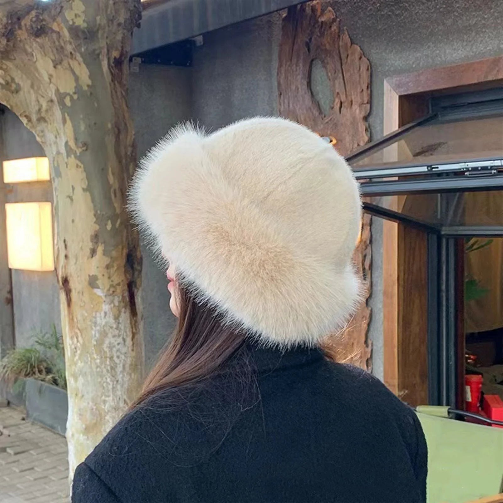 Person wearing a large white fur hat in an outdoor setting.