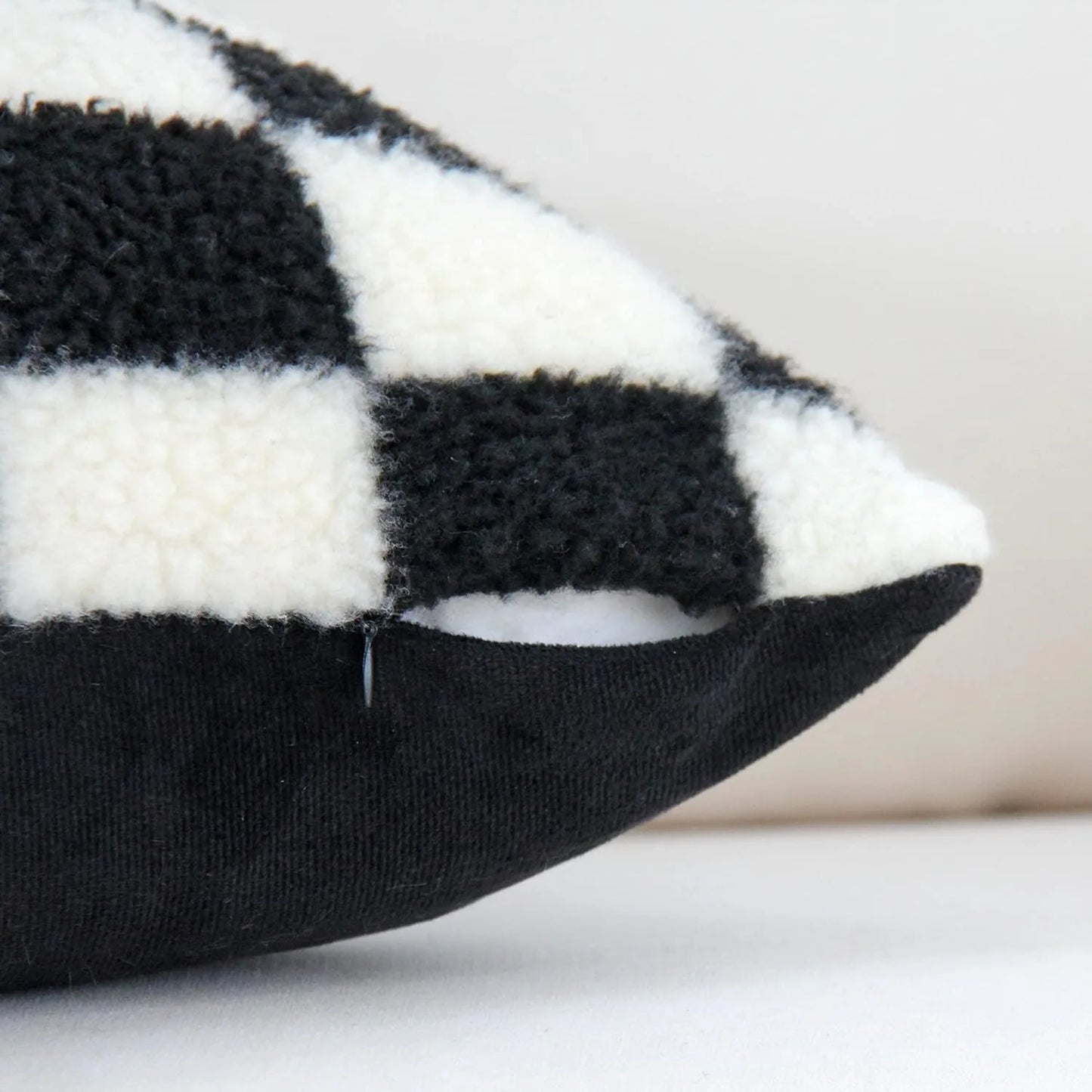 Black and white checkered pillow on a neutral background