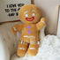 Plush gingerbread man toy on a couch with a decorative wall in the background