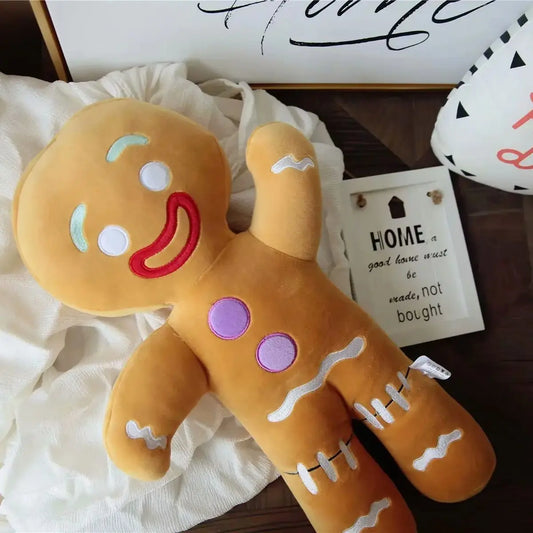 Plush Gingerbread toy with a smiling face on a wooden surface with decorative items.