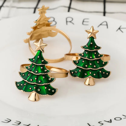Two green Christmas tree-shaped rings with gold bases on a white surface.