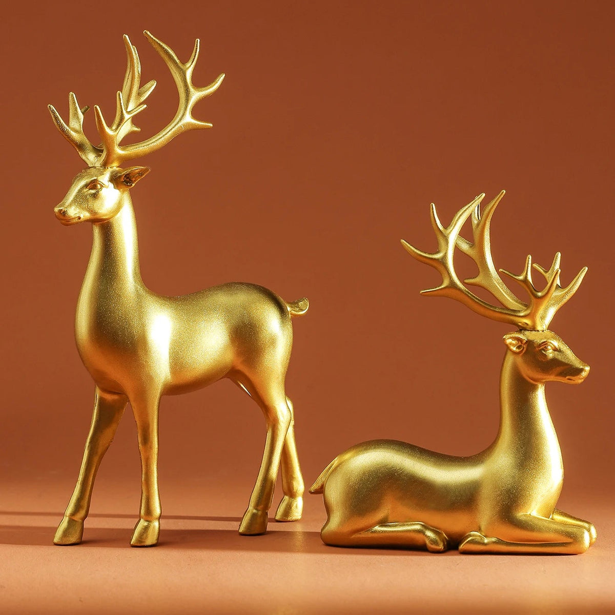 Two gold deer figurines on a brown background