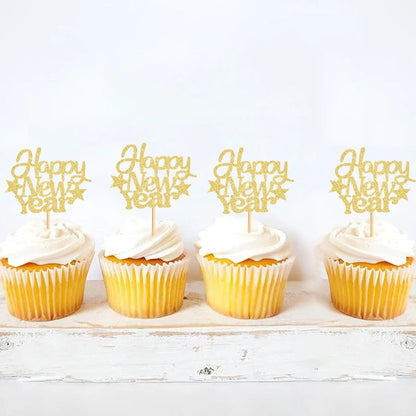 Four cupcakes with white frosting and yellow wrappers, each topped with a 'Happy New Year' topper on a light wooden surface.
