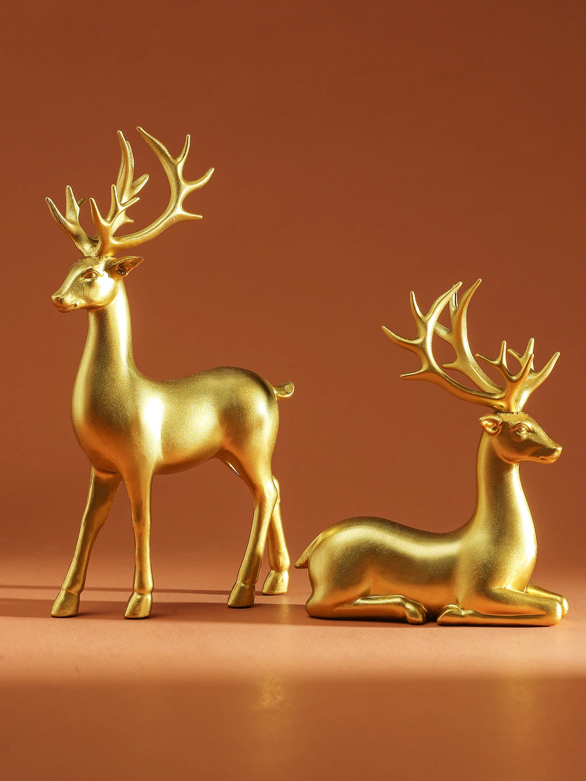 Two gold deer figurines on a brown background