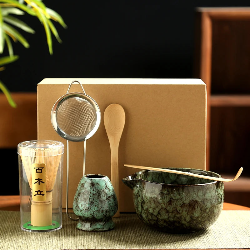 Tea-making set with a green ceramic bowl, wooden spoon, and other tools on a woven mat.