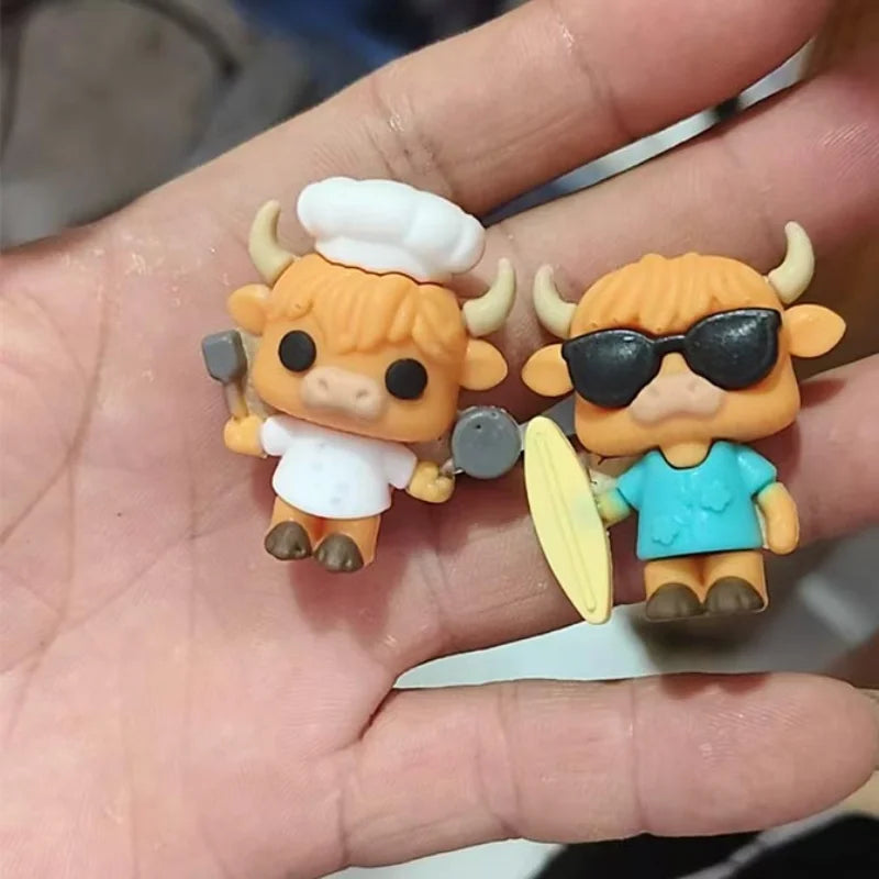 Two small figurines of a cow in chef and surfer outfits held in a hand.