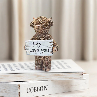 Wooden figurine holding a 'I love you' sign on top of books with a blurred background