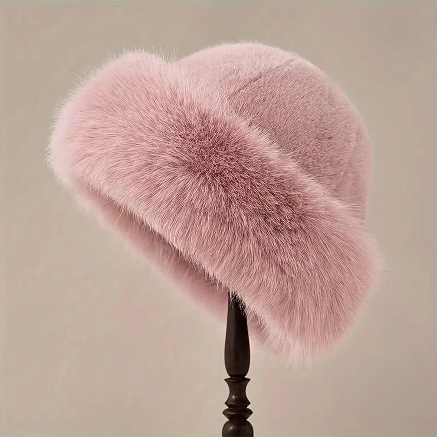 Pink fur hat on a stand against a beige background
