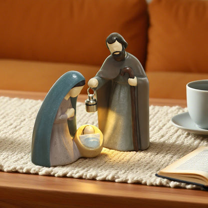 Ceramic nativity scene figurines on a table with a cup and book in the background.