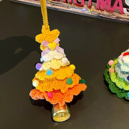 Crocheted orange Christmas tree ornament with colorful decorations on a dark surface.