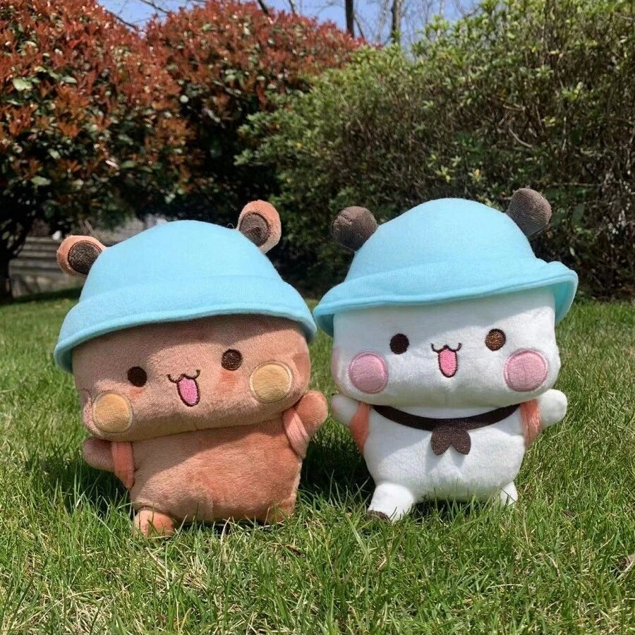 Two plush toys with blue hats sitting on grass - Panda & Bear