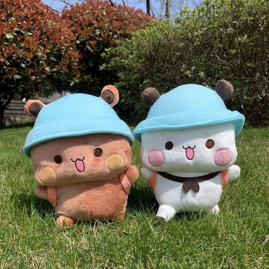 Two plush toys with blue hats sitting on grass - Panda & Bear