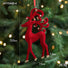 Red reindeer ornament with gold accents on a Christmas tree, showing measurements and weight.