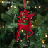 Red deer-shaped Christmas ornament with measurements on a green tree background