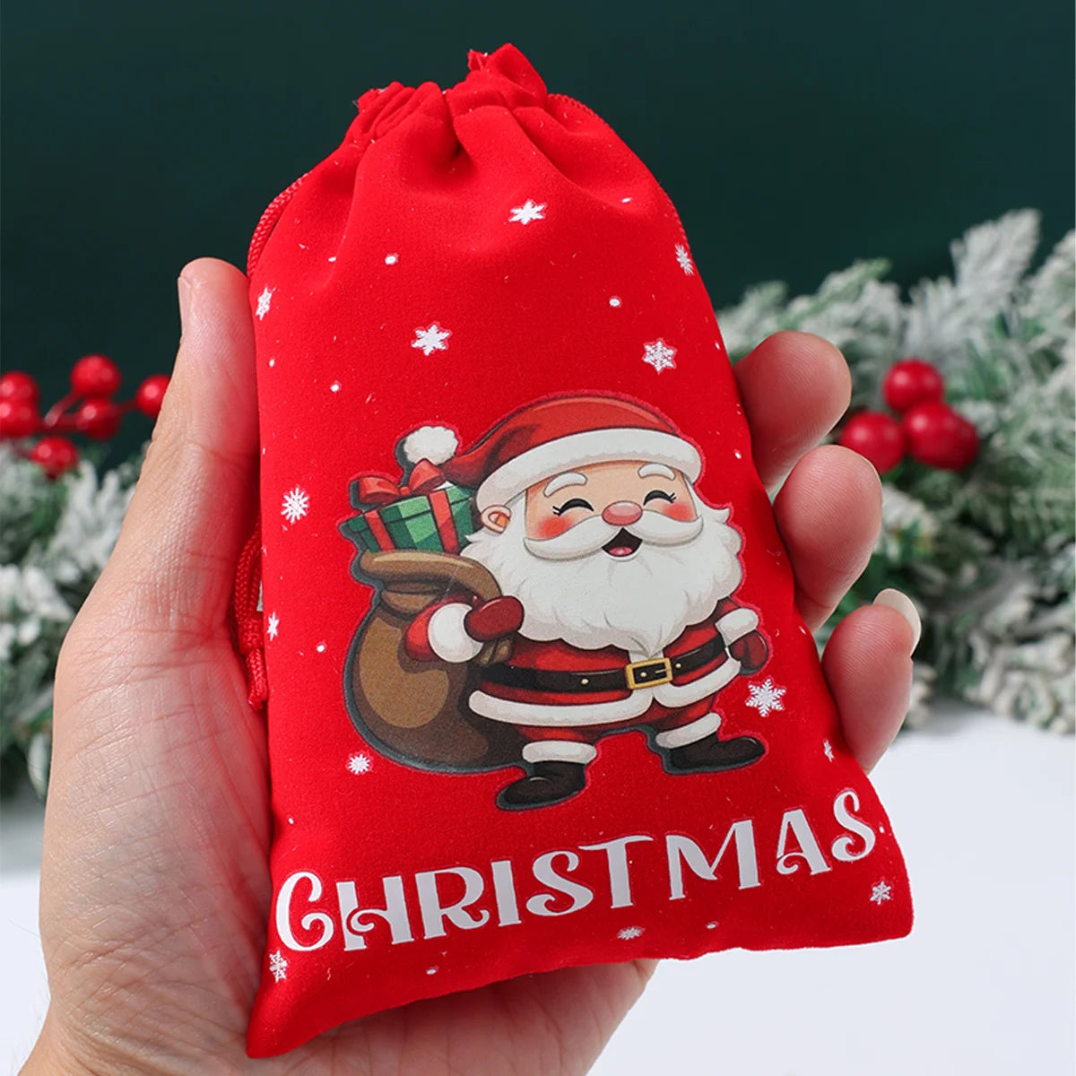 Red Christmas drawstring bag with Santa Claus design held by a hand against a festive background.