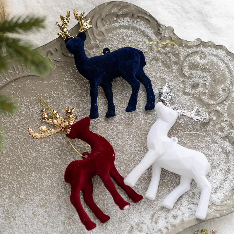 Three decorative deer figurines in blue, red, and white on a textured surface.