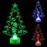 Three Christmas tree-shaped night lights in green, blue, and red on a black background.